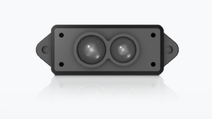 A LiDAR (Light Detection and Ranging) sensor is shown. The sensor has a rectangular grey casing with two large, circular lenses positioned side-by-side at the top. Four small screws are near each corner of the grey casing. This sensor is likely used for object or environment detection.